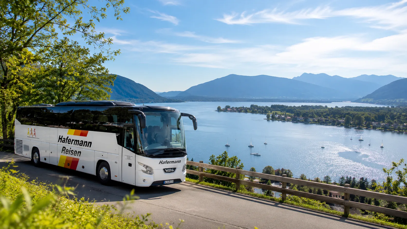 Ein Hafermann-Reisebus fährt auf einer Panorama-Küstenstraße oberhalb eines sonnig blauen Sees mit Bergen im Hintergrund