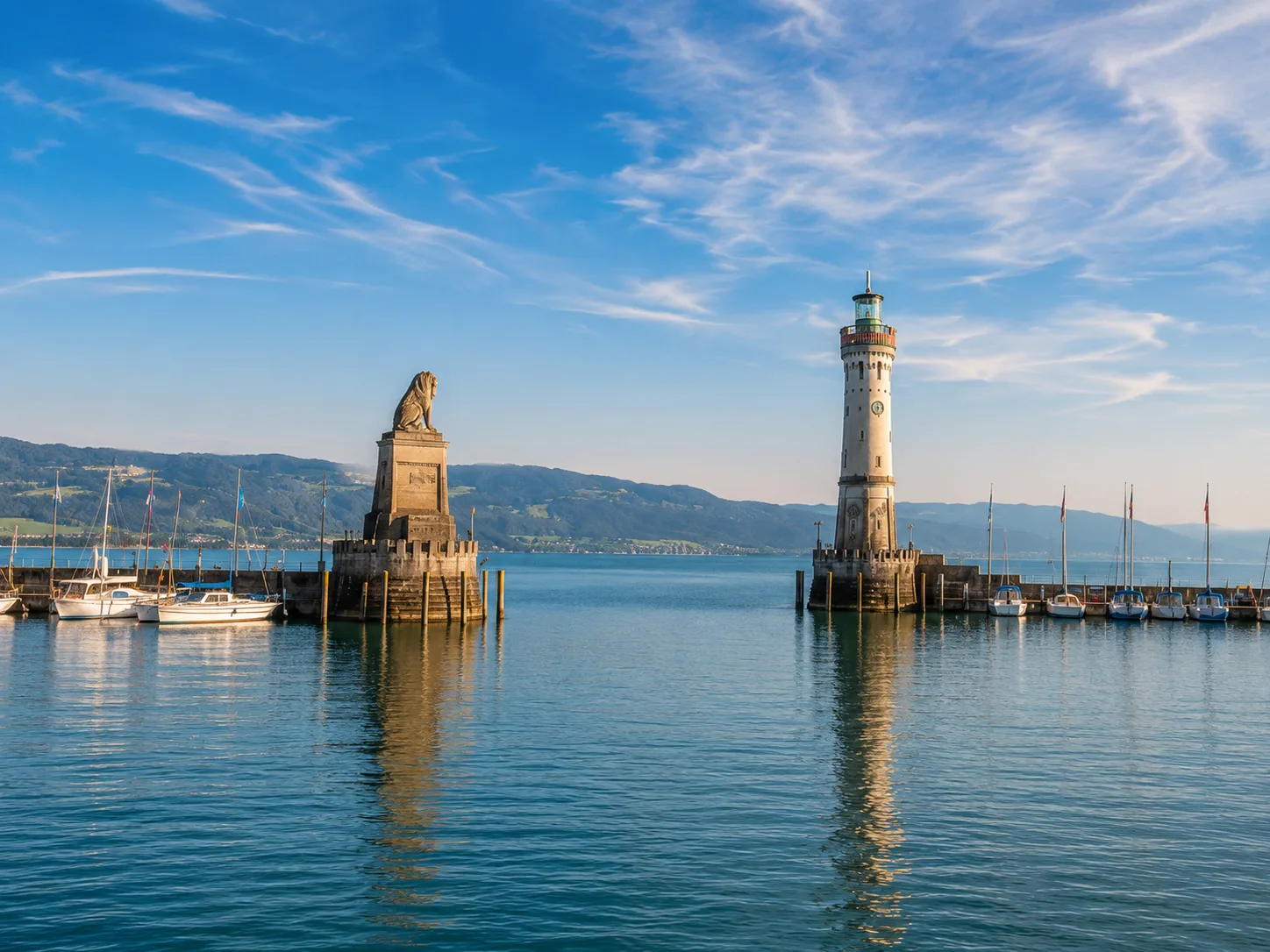 Hafeneinfahrt von Lindau am Bodensee mit dem bayerischen Löwen und Leuchtturm vor Alpenpanorama bei sonnigem Wetter