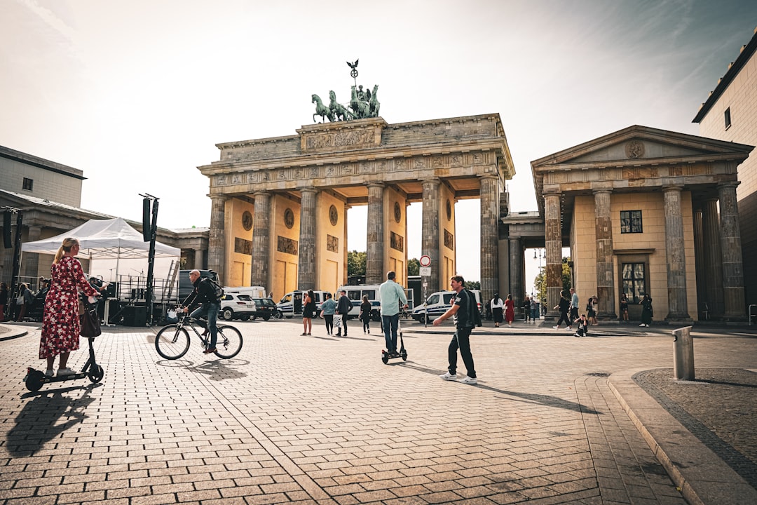 Belebter Pariser Platz in Berlin mit Passanten und Radfahrern vor dem Brandenburger Tor bei sonnigem Wetter