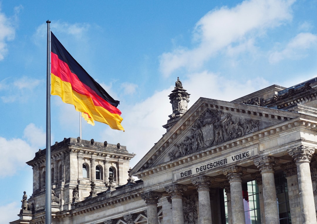 Wehende Deutschlandflagge vor der Fassade des Reichstagsgebäudes in Berlin bei blauem Himmel