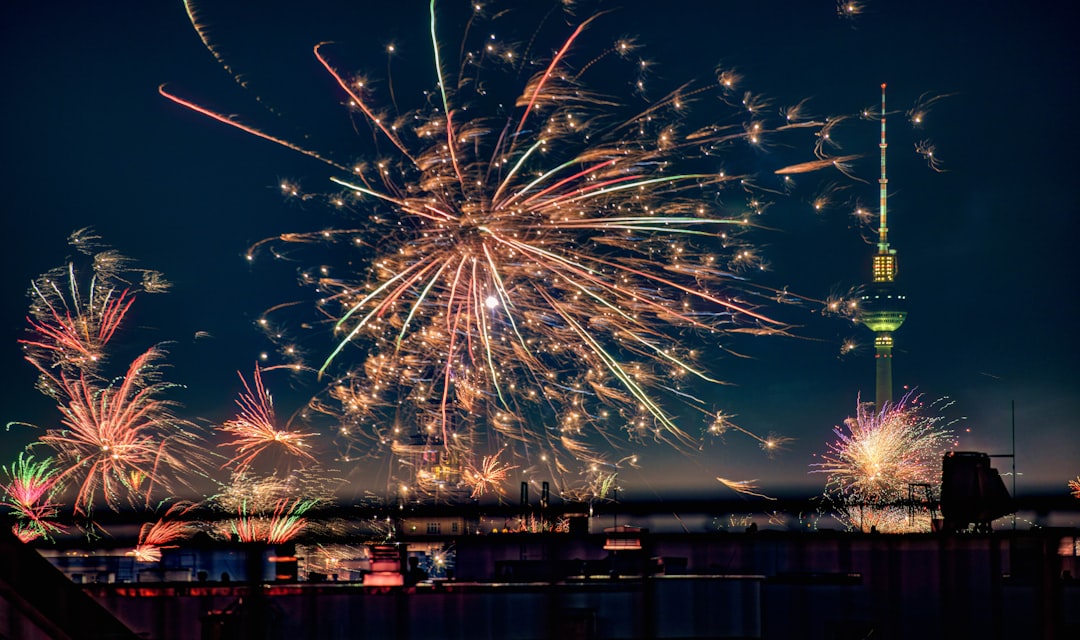 Buntes Silvesterfeuerwerk über der nächtlichen Skyline von Berlin mit dem beleuchteten Fernsehturm im Hintergrund