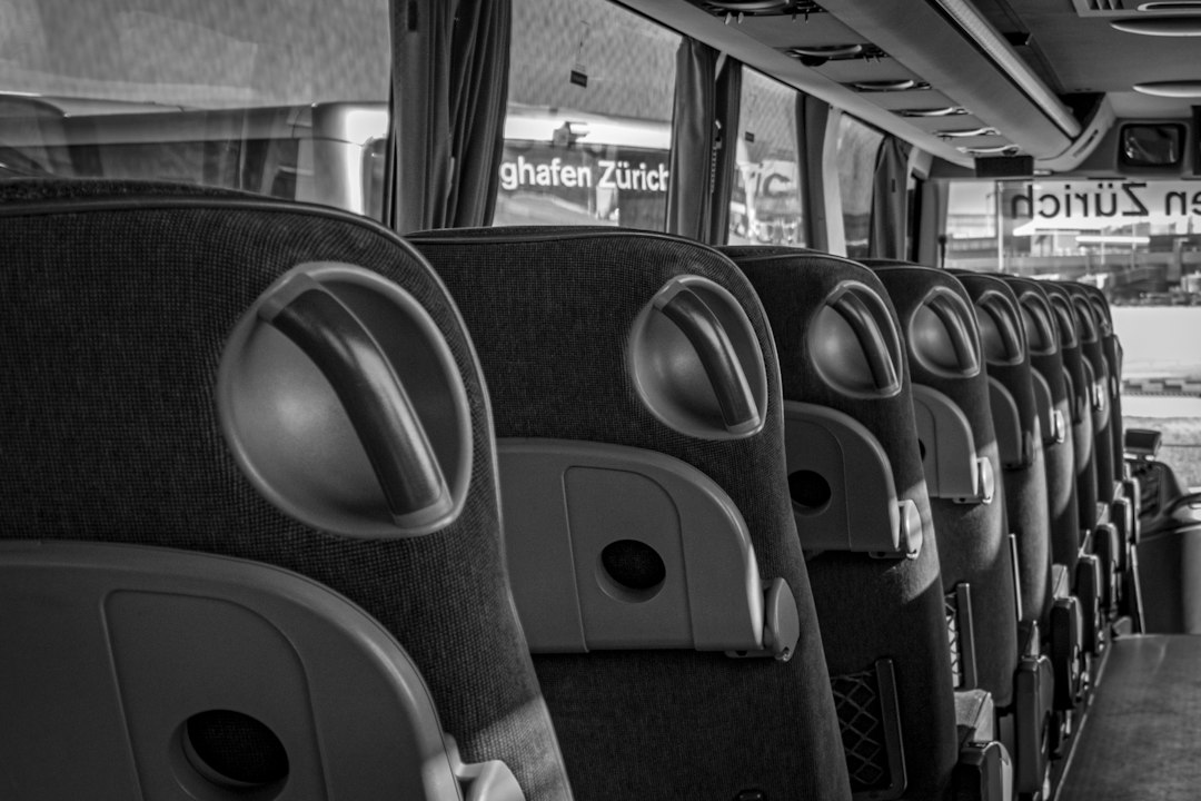 Schwarz-Weiß-Aufnahme einer leeren Sitzreihe in einem modernen Reisebus am Flughafen Zürich