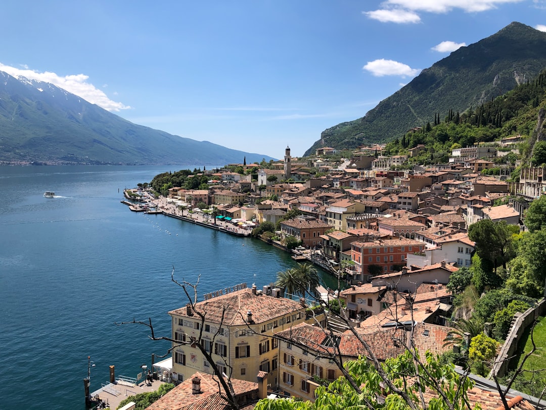 Panoramablick auf das sonnige Limone sul Garda am tiefblauen Gardasee vor steilen Berghängen